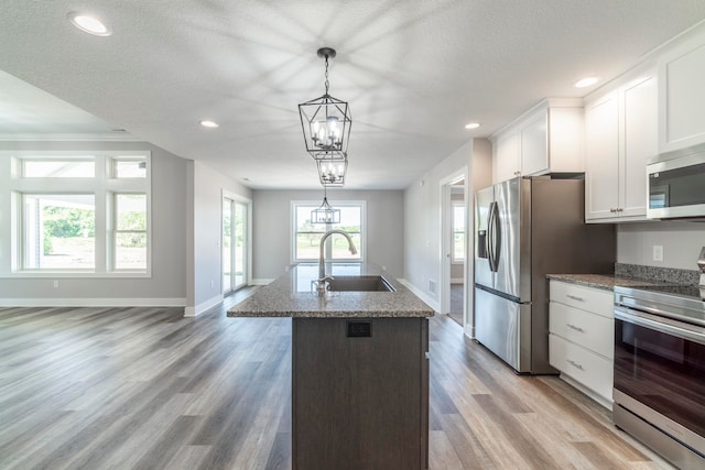 kitchen with light hardwood / wood-style flooring, stainless steel appliances, white cabinetry, sink, and a center island with sink