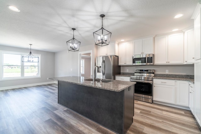 kitchen featuring white cabinetry, stainless steel appliances, an island with sink, sink, and light hardwood / wood-style floors