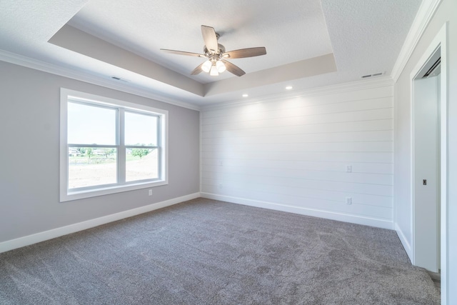 carpeted empty room featuring a tray ceiling, a textured ceiling, ornamental molding, and ceiling fan