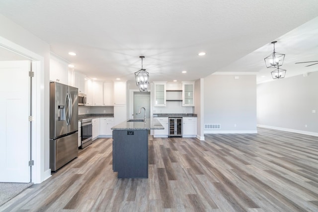 kitchen featuring pendant lighting, beverage cooler, light hardwood / wood-style floors, stainless steel appliances, and sink