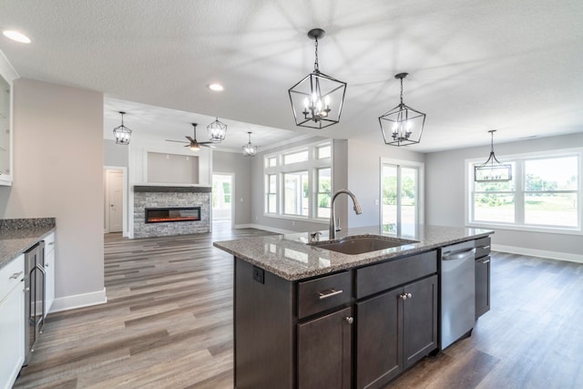 kitchen featuring pendant lighting, dark brown cabinets, sink, and light stone counters