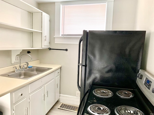 kitchen featuring refrigerator, sink, stainless steel range with electric cooktop, and white cabinets