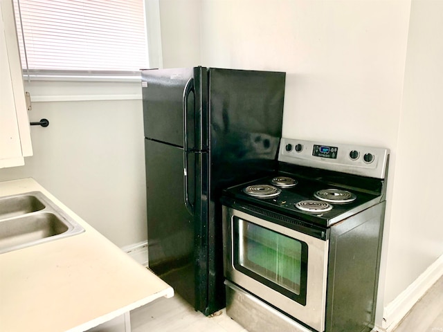 kitchen with white cabinetry, sink, and electric range