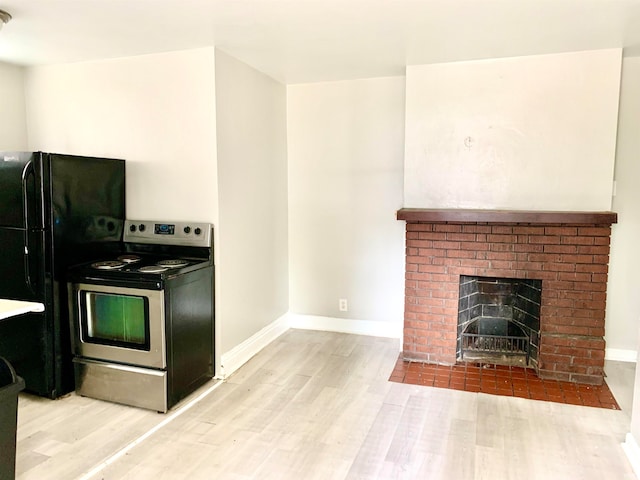 kitchen with stainless steel electric stove, black fridge, wood-type flooring, and a fireplace