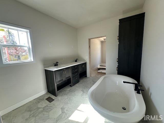 full bathroom featuring a freestanding tub, baseboards, baseboard heating, and double vanity