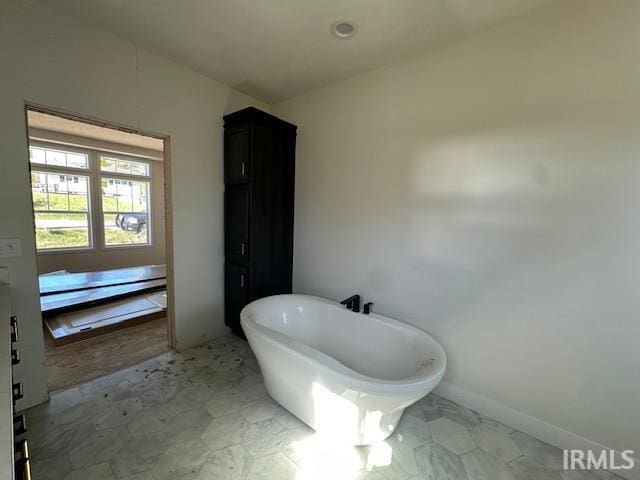 bathroom with a freestanding tub and baseboards