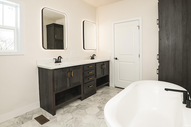 bathroom featuring a freestanding tub, a sink, baseboards, marble finish floor, and double vanity