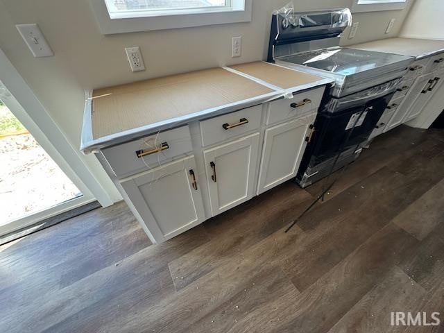 kitchen with light countertops, stainless steel range with electric cooktop, dark wood finished floors, and white cabinets