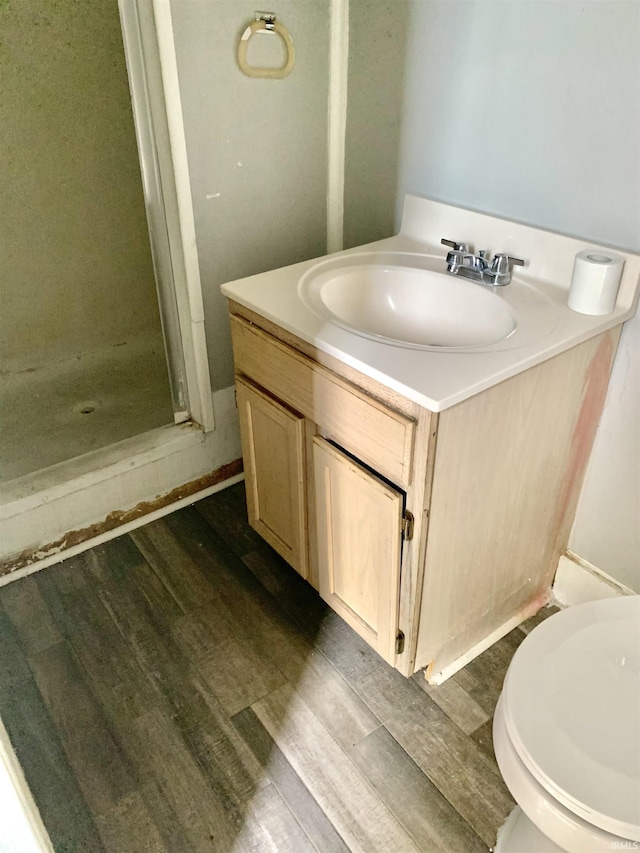 bathroom featuring hardwood / wood-style flooring, vanity, toilet, and walk in shower