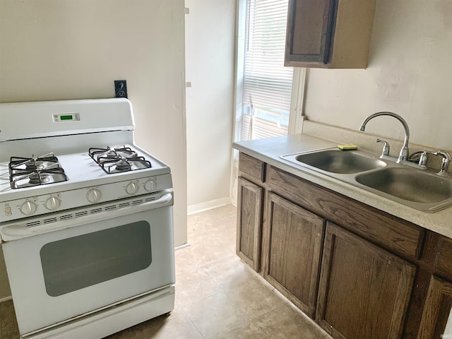 kitchen with sink, white range with gas stovetop, and light tile patterned floors