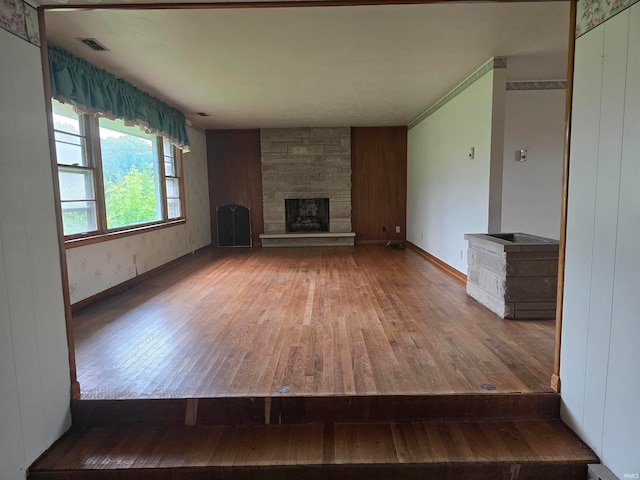 unfurnished living room featuring hardwood / wood-style flooring and a stone fireplace