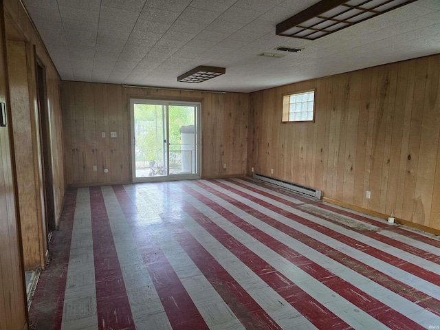 unfurnished room featuring baseboard heating and wood walls