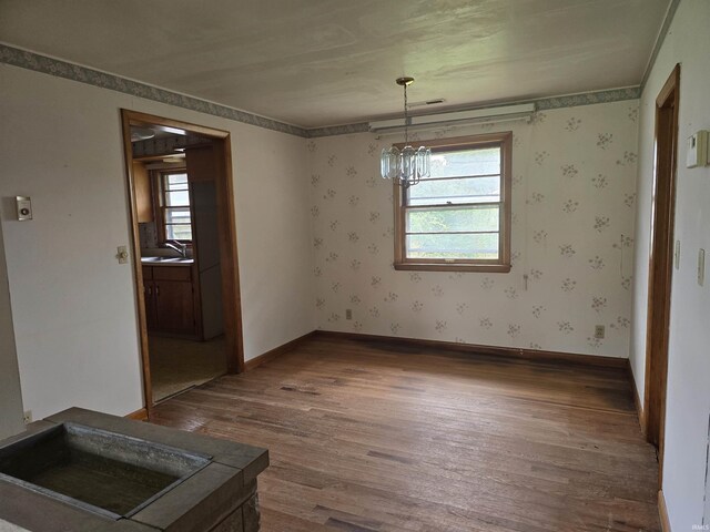 spare room with hardwood / wood-style floors, sink, and a notable chandelier