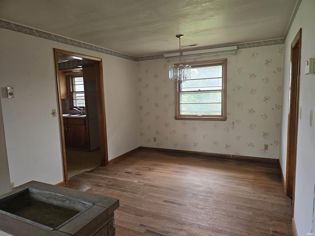 unfurnished dining area featuring dark wood-type flooring, a wealth of natural light, and an inviting chandelier