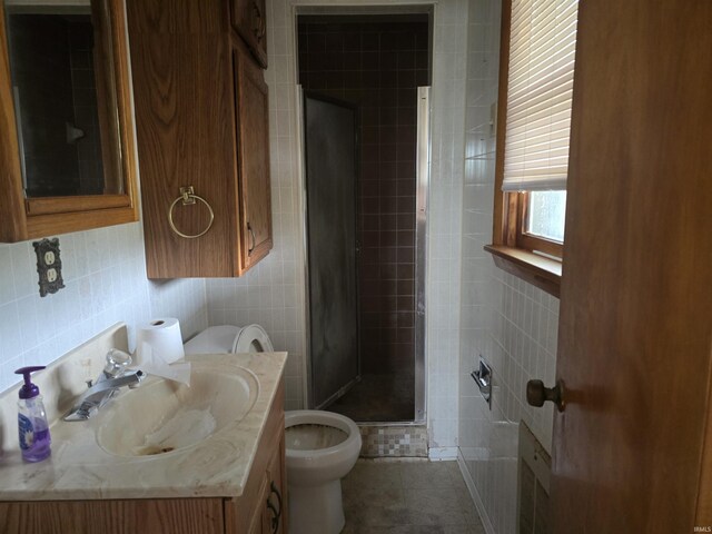 bathroom with toilet, tile patterned floors, tile walls, a tile shower, and vanity