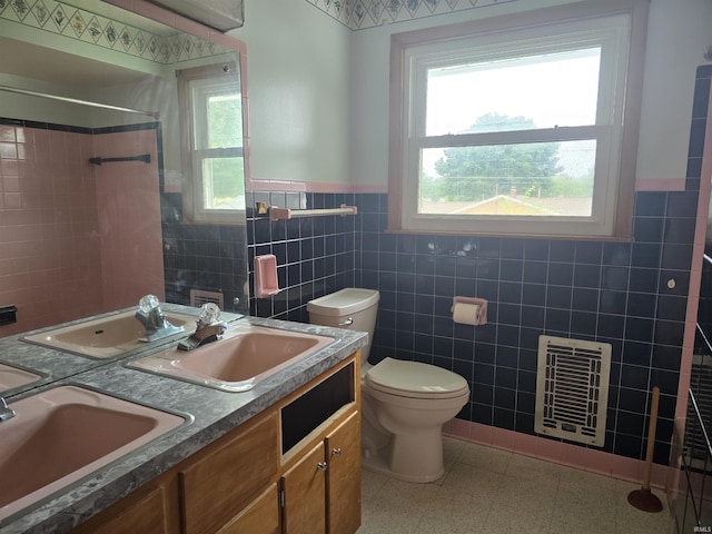 bathroom featuring tiled shower, toilet, heating unit, tile walls, and vanity