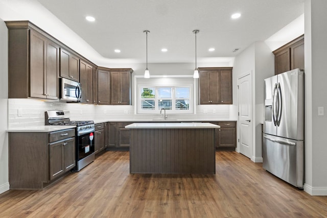 kitchen with dark brown cabinetry, appliances with stainless steel finishes, hanging light fixtures, and dark hardwood / wood-style flooring