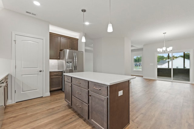 kitchen featuring pendant lighting, light wood-type flooring, a center island, an inviting chandelier, and dark brown cabinetry