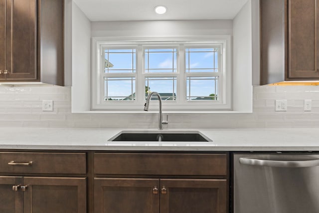 kitchen with dark brown cabinets, stainless steel dishwasher, sink, and tasteful backsplash