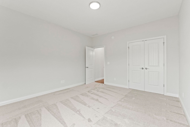 unfurnished bedroom featuring a closet and light colored carpet