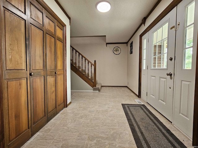 foyer entrance with ornamental molding and a textured ceiling