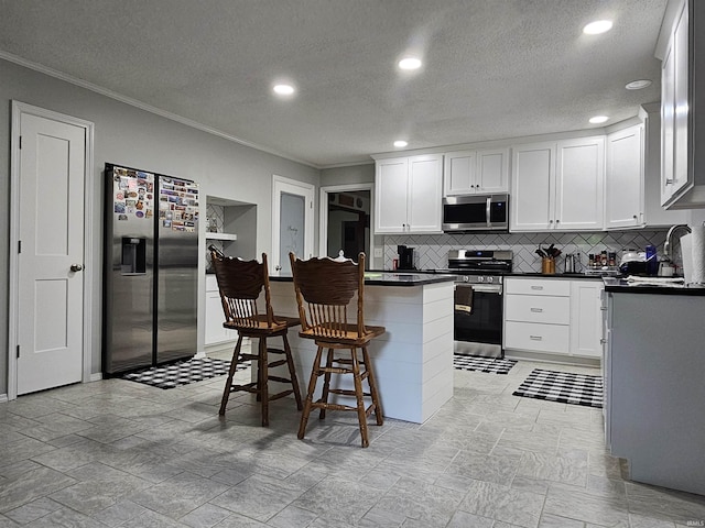 kitchen featuring a breakfast bar, white cabinetry, backsplash, ornamental molding, and stainless steel appliances