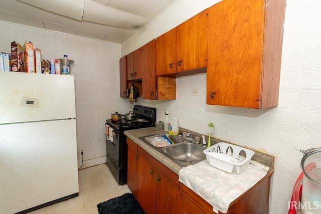 kitchen featuring sink, white fridge, light tile patterned floors, and black range with electric cooktop