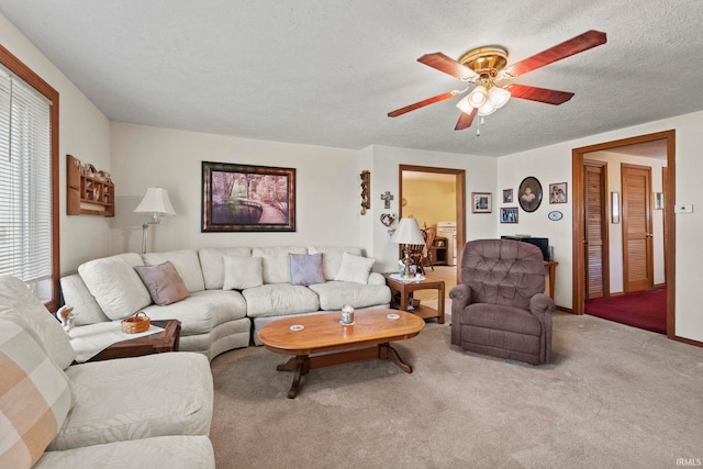 living room featuring ceiling fan, a textured ceiling, and carpet