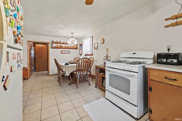 kitchen featuring hanging light fixtures, a notable chandelier, white gas range oven, and light tile patterned flooring