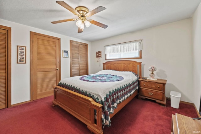 bedroom featuring ceiling fan, multiple closets, and dark colored carpet