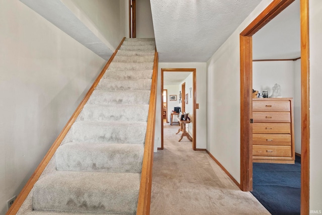 stairs featuring carpet and a textured ceiling