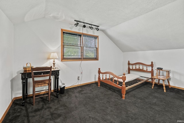 bedroom featuring vaulted ceiling, track lighting, a textured ceiling, and dark colored carpet