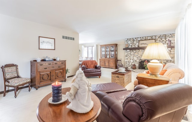 carpeted living room featuring a stone fireplace