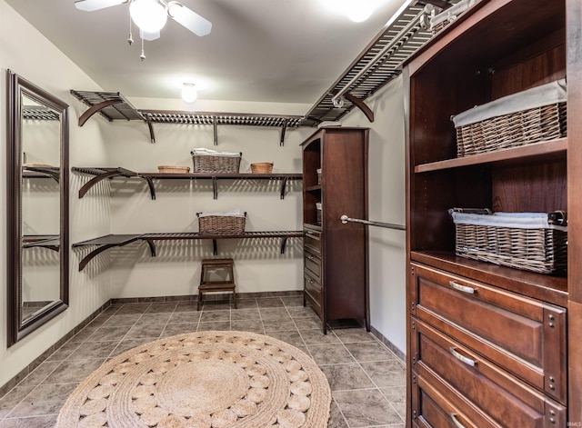 walk in closet featuring dark tile patterned flooring and ceiling fan