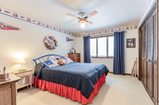 bedroom with light colored carpet, ceiling fan, and a closet