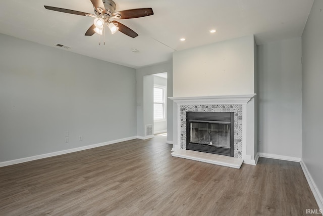 unfurnished living room featuring a tiled fireplace, hardwood / wood-style flooring, and ceiling fan