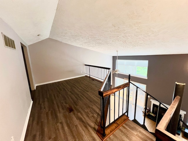 stairway featuring a textured ceiling, ceiling fan, wood-type flooring, and lofted ceiling