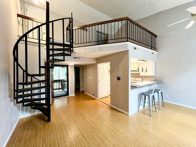 unfurnished living room featuring ceiling fan, high vaulted ceiling, light hardwood / wood-style flooring, and a wealth of natural light