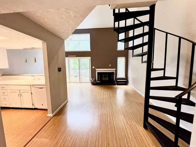 stairs with high vaulted ceiling and hardwood / wood-style floors