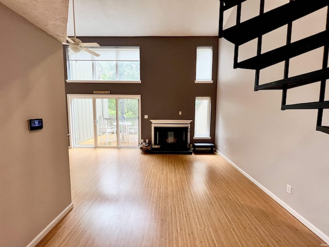 living room with high vaulted ceiling, ceiling fan, and light wood-type flooring