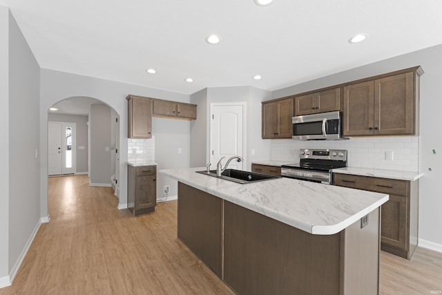 kitchen featuring appliances with stainless steel finishes, light hardwood / wood-style flooring, an island with sink, and sink