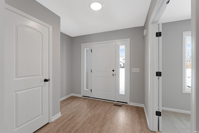 foyer entrance with light wood-type flooring and a wealth of natural light