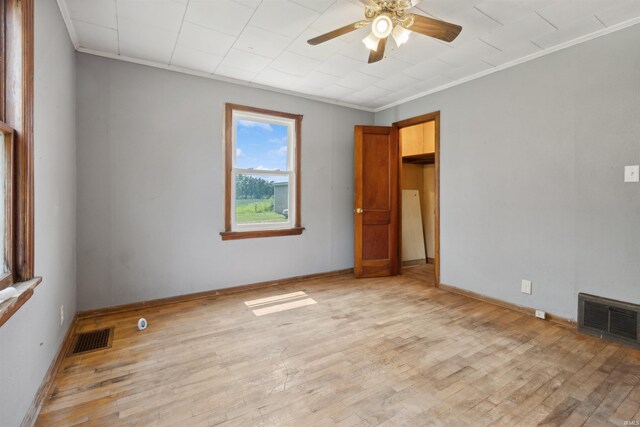 empty room featuring light wood-style flooring, visible vents, and crown molding