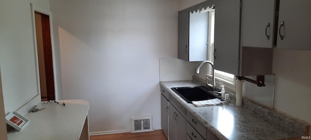 kitchen featuring light wood-style flooring, a sink, visible vents, baseboards, and light countertops