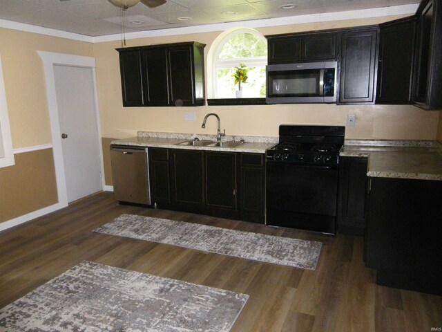 kitchen with ceiling fan, stainless steel appliances, sink, light stone counters, and dark hardwood / wood-style floors