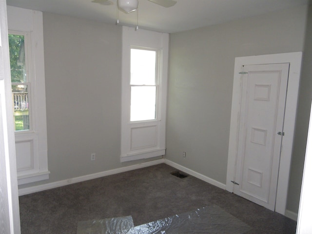 unfurnished room featuring ceiling fan and dark carpet