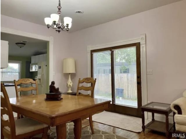 dining space with hardwood / wood-style flooring and an inviting chandelier