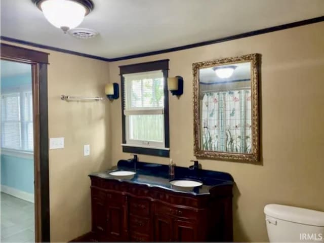 bathroom featuring vanity, ornamental molding, and toilet