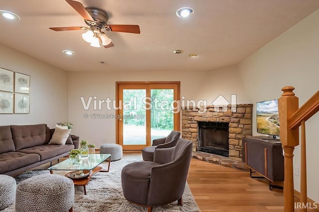 living room featuring ceiling fan, a fireplace, and light wood-type flooring