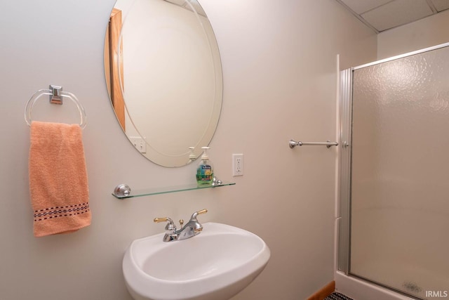 bathroom featuring a shower with door and sink